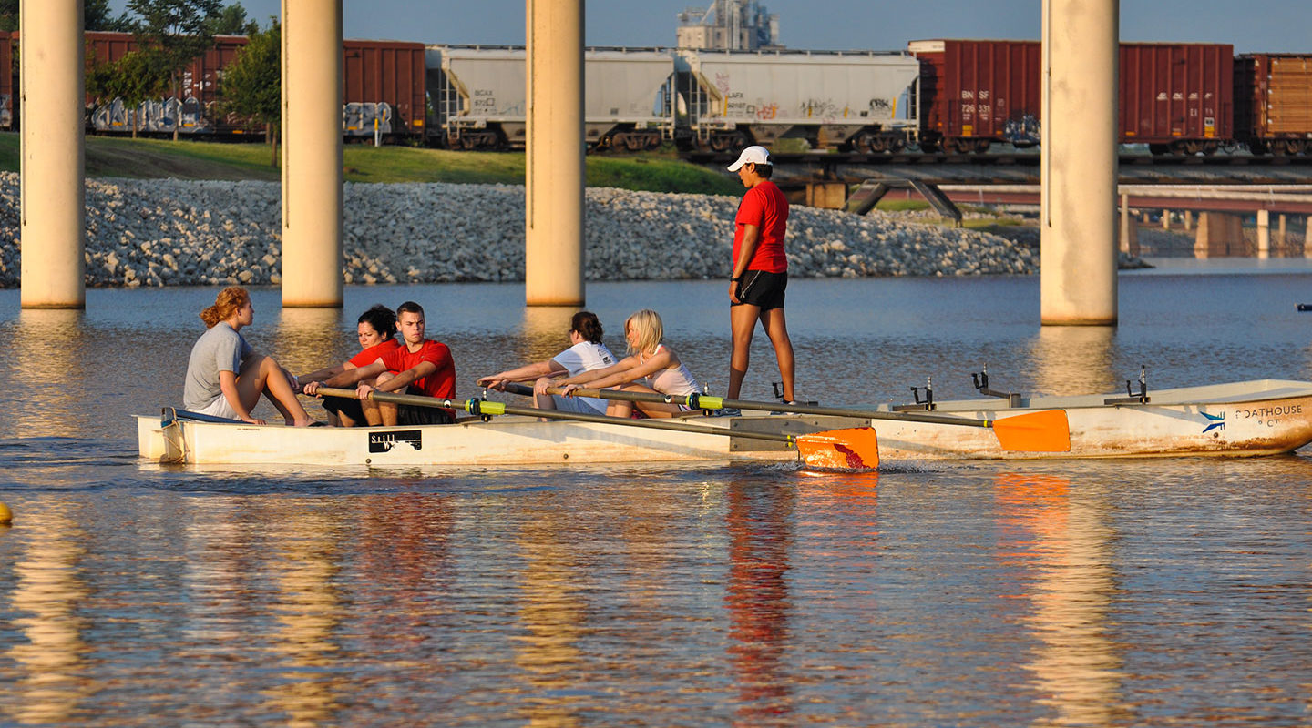 Image of group of people learning to row in a rowing barge on the Oklahoma River