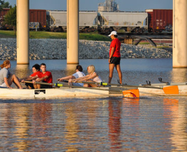 Image of group of people learning to row in a rowing barge on the Oklahoma River