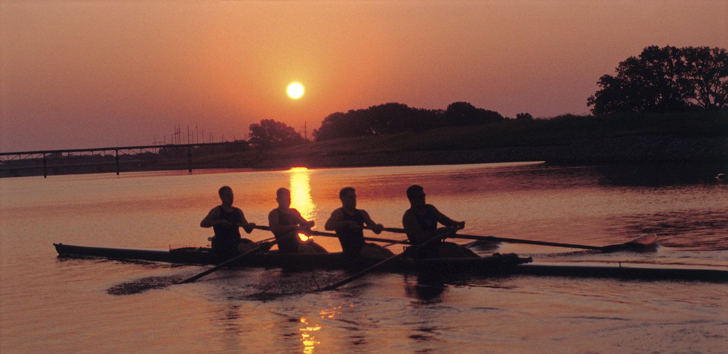 Image of four men rowing at sunrise on the Oklahoma River